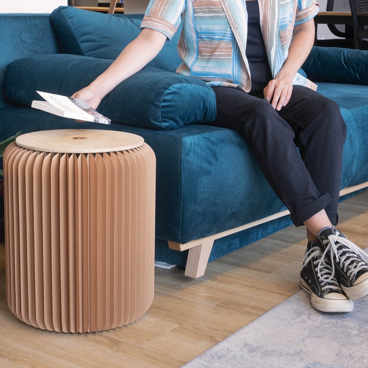 tabouret pliable marron avec assise en bambou à coté d'un canapé