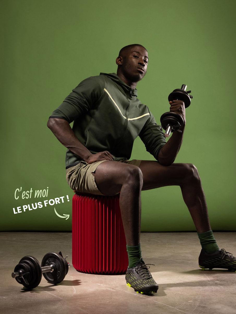 Un homme sportif assis sur un tabouret rouge