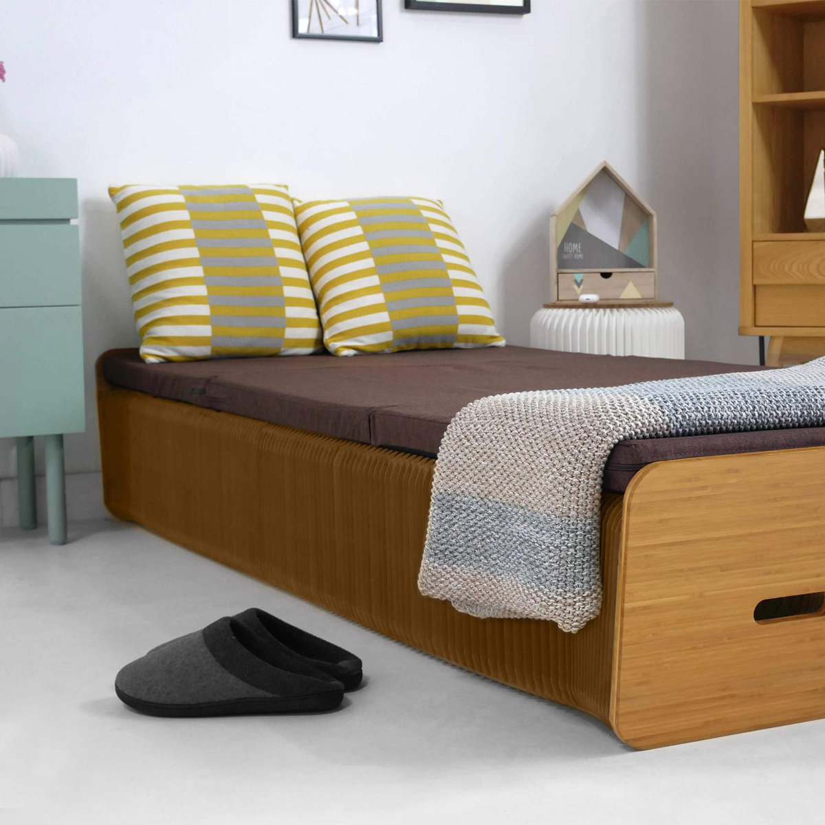 Ici, le lit en carton alvéolé est déplié et va jusqu'à 2 mètres. Le matelas est inclu avec et le lit supporte jusqu'à 500 kgs. Vous pouvez dormir dessus en toute tranquilité et confort.