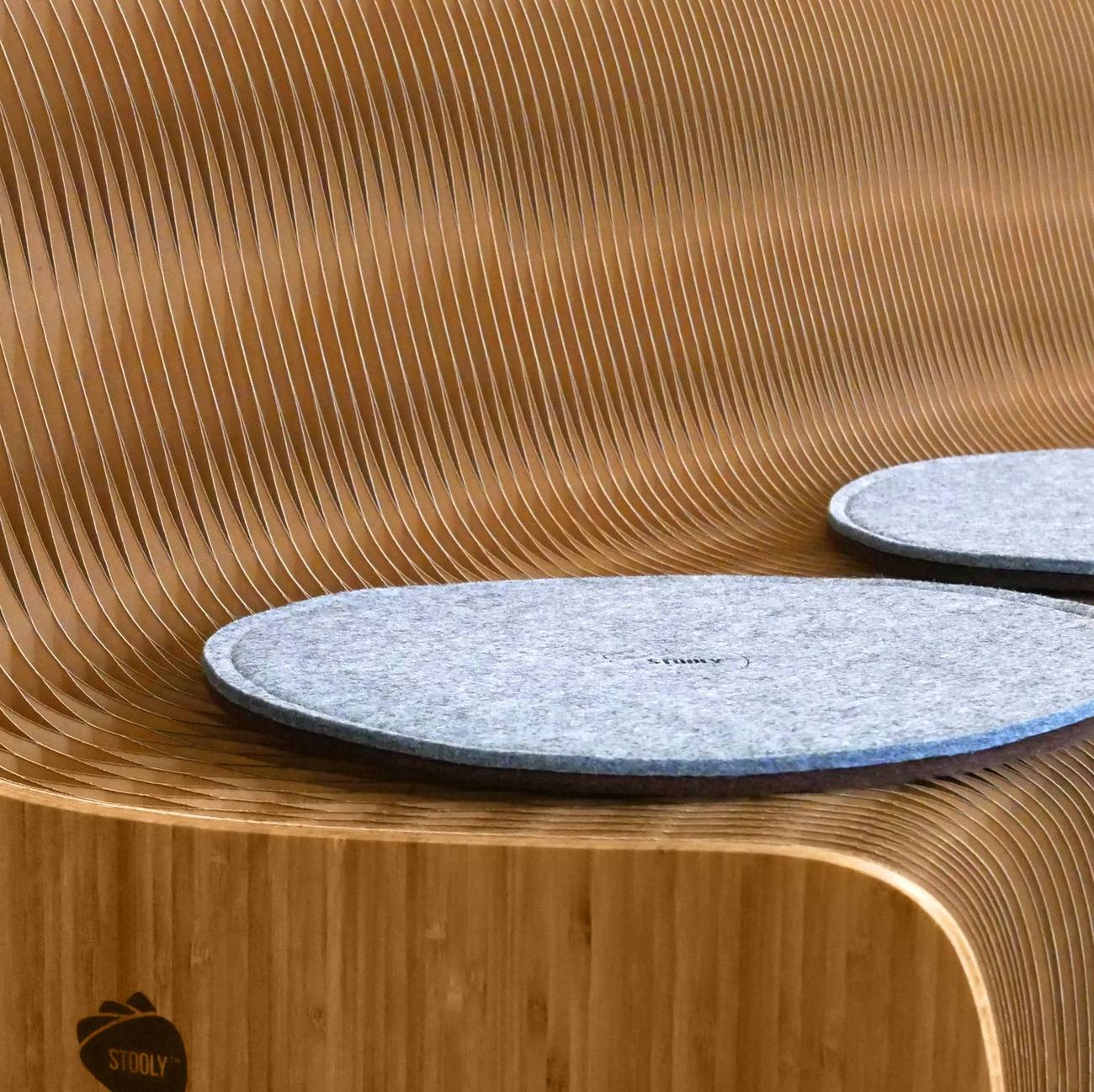 Galette en feutrine sur le sofa stooly flexible en carton alvéolé et finition en bamboo.
